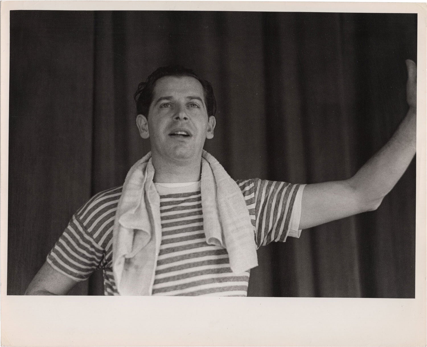 A candid shot of Milton Berle adjusting his tie, exuding confidence and charm